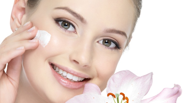 Smiling woman with lily applying cream