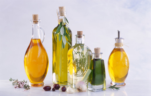 Various oils in bottles with rosemary sprig, olives and garlic