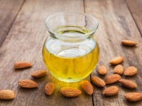 Almond oil in glass bottle and almonds